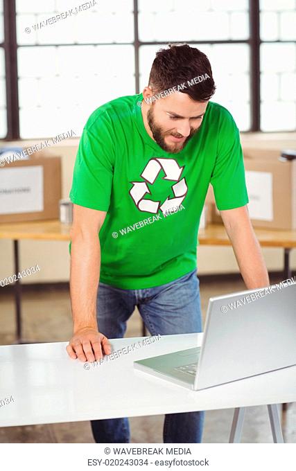 Man in recycling symbol tshirt working on laptop