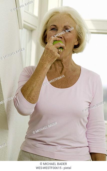 Senior woman eating fruit, portrait