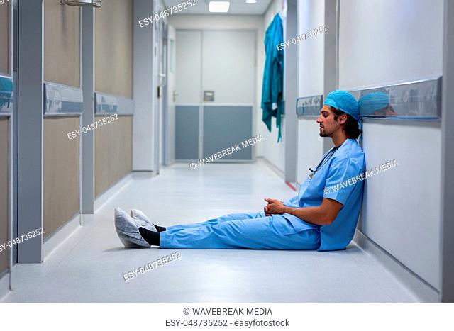 Male surgeon leaning at hospital corridor