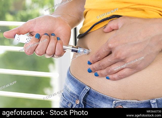 Germany, Freiburg, Mid adult woman injecting insulin