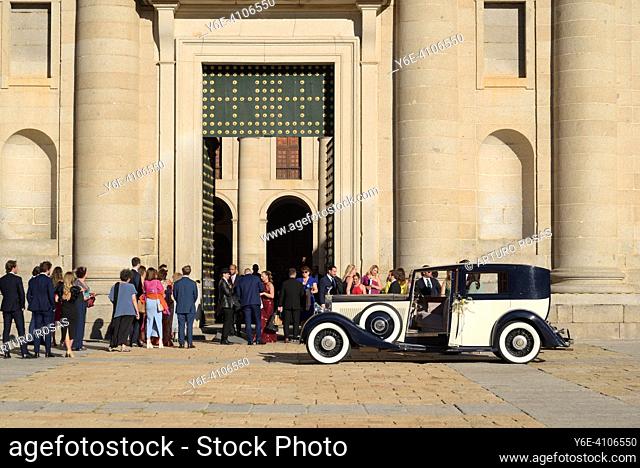 Bride car and guests waiting the newlyweds at the doors of the Monastery of San Lorenzo de El Escorial in the Community of Madrid
