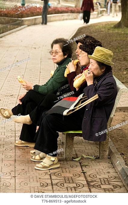 4 women eating sandwiches in the park in Hanoi Vietnam