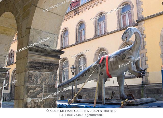 23.05.2018, Saxony-Anhalt, Halberstadt: The model of a Plateosaurus drives on the loading area of a truck through the narrow streets of the old town