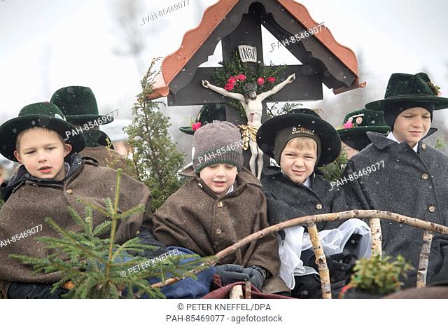 Children wearing traditional festive costumes in on a traditional carriage during the Leonhardifahrt procession through a meadow at the Calvary hill in Bad...