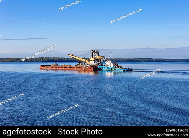 Yaroslavl Region, Russia - September 11, 2021: Tugboat Captain Petrov and a barge with sand float on the Volga River