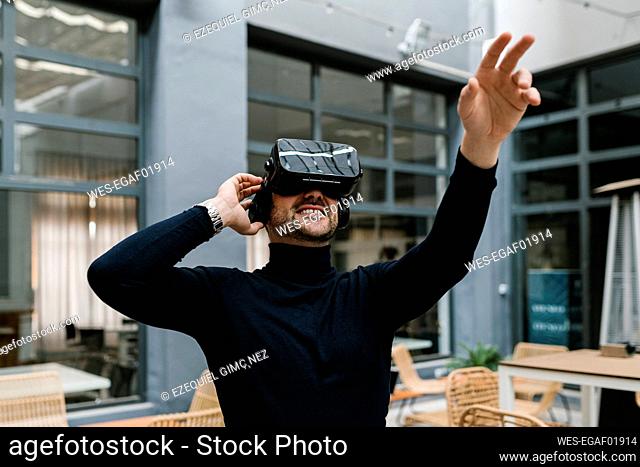 Businessman stretching hand while using virtual reality headset at cafe