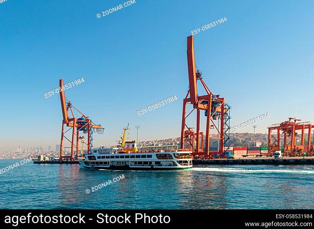 Day shot of the cranes in the shipyard of the Port of Haydarpasha, and passing ferry boat with city view in the background, Istanbul, Turkey