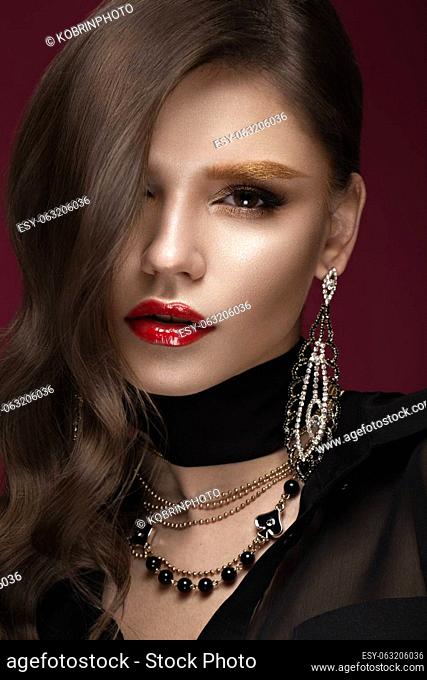 Beautiful girl with red lips and golden eyebrows, curls in Hollywood style. Beauty face. Photo taken in the studio