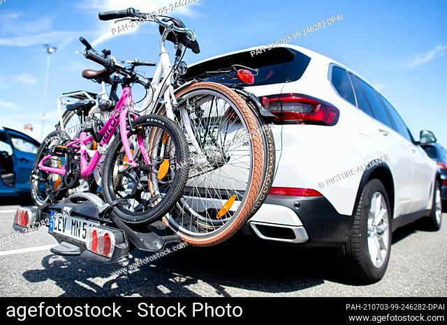 03 July 2021, Lower Saxony, Norddeich: A car with a family's bicycles on a bicycle rack stands in a queue at the ferry port for departure to the island of...