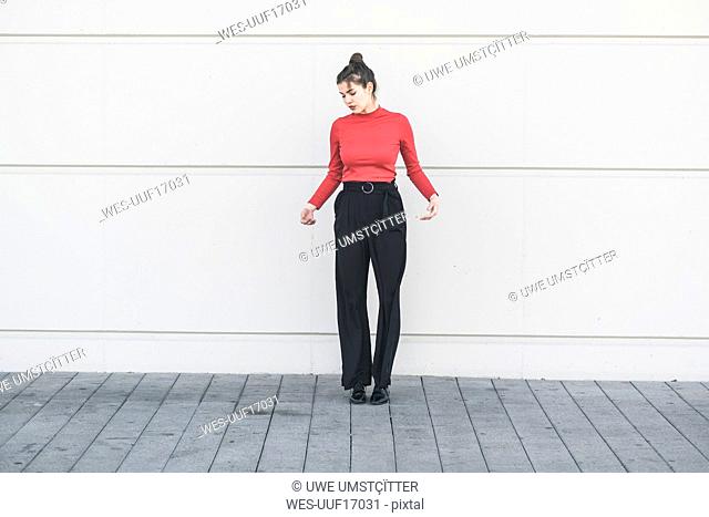 Elegant young woman standing at a wall