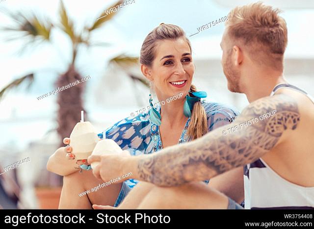 Close-up of young couple holding coconut water and looking at each other