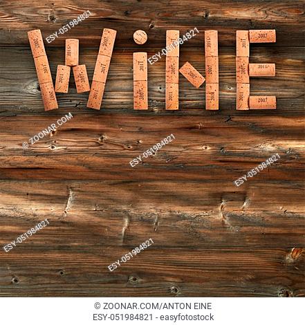 Word WINE shaped by natural wooden wine bottle corks of different vintage years over background of dark old wooden planks
