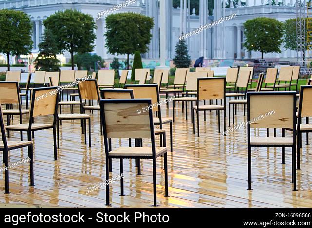 Wooden chairs stand in the rain outside