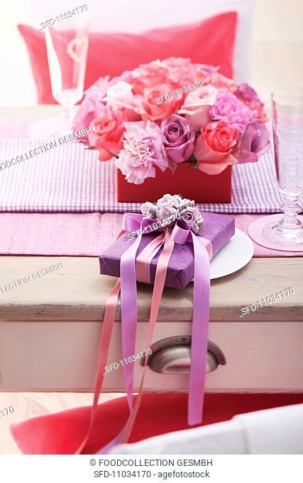 Table with flower arrangement and present