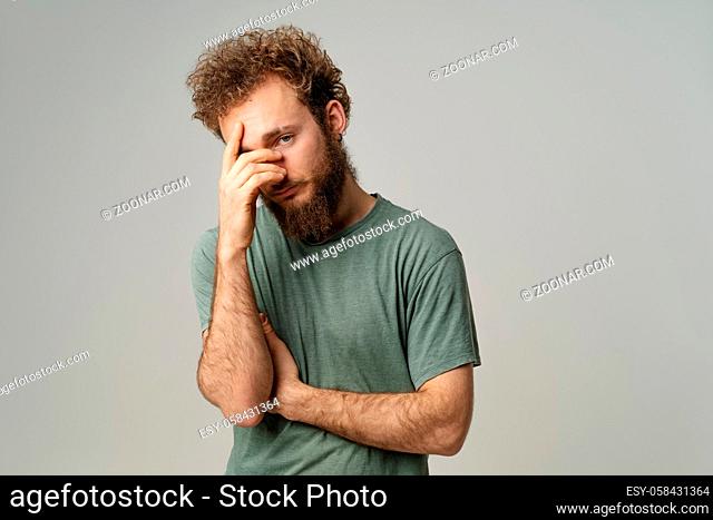 Ashamed or facepalm hiding face young man covered his with hand pry with his eye, curly hair in olive t-shirt isolated on white background