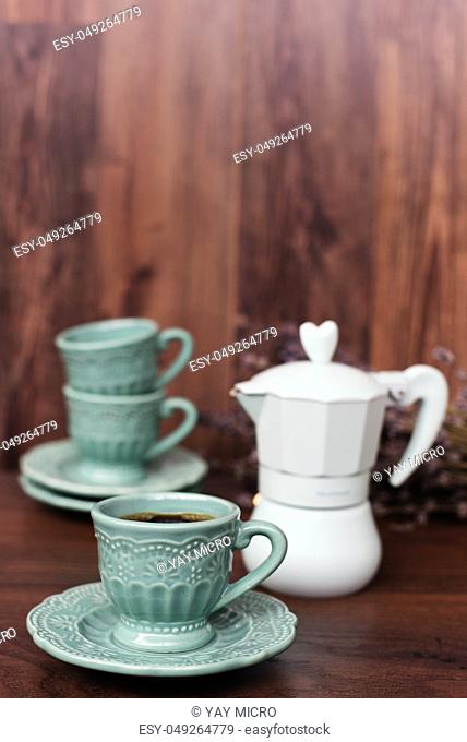 Cup of coffee and Italian coffee maker in blue, scent of lavender. Dark wooden background