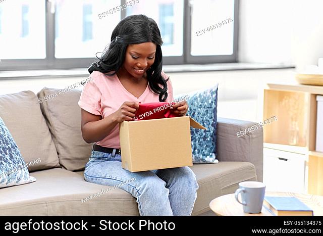 african american woman opening parcel box at home