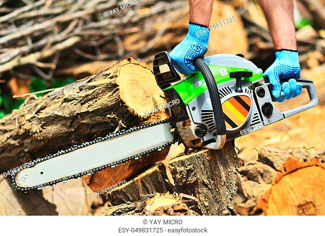 A man runs a chainsaw, removes a piece of wood