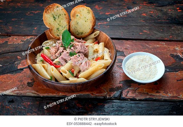 Pasta with tuna, garlic bread and parmesan cheese aside isolated on rustic wooden background