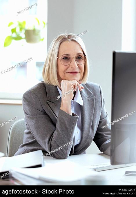 Businesswoman with hand on chin using computer in office