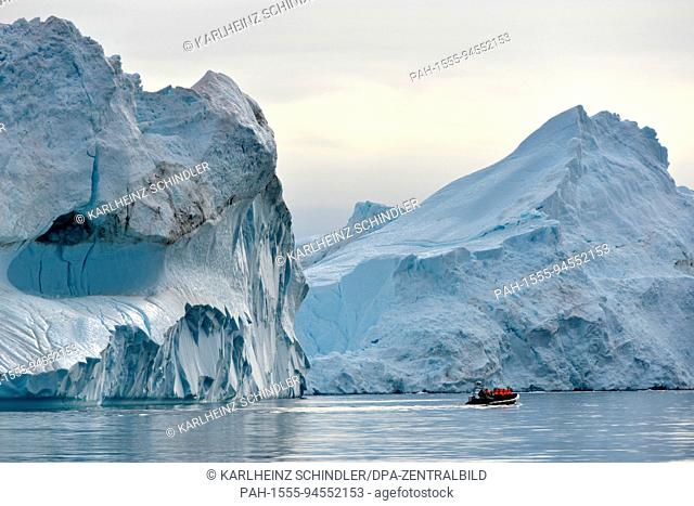 A fishing boat with tourists makes its way through icebergs floating in the fjord near Ilulissat on the west coast of Greenland