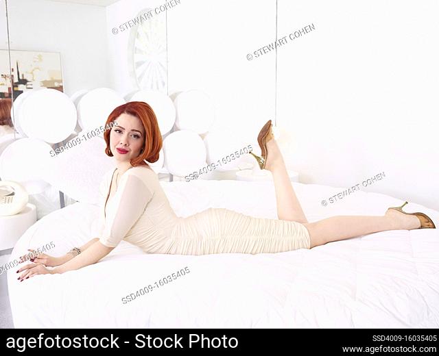 Portrait of a woman laying on a bed in a mid-century style home