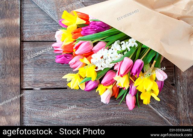Blumenstrauss mit Tulpen und Narzissen auf rustikalem Hintergrund aus Holz