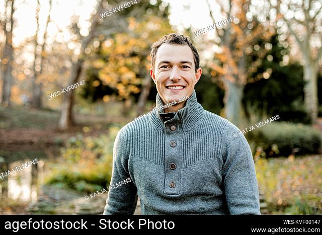 Smiling handsome man sitting in public park