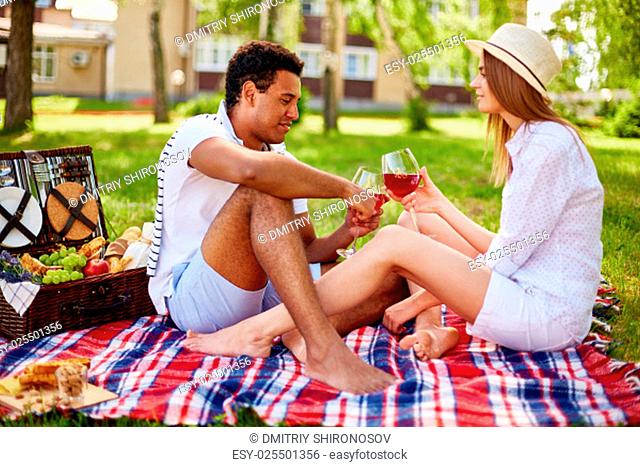 Happy young couple toasting during picnic in urban environment