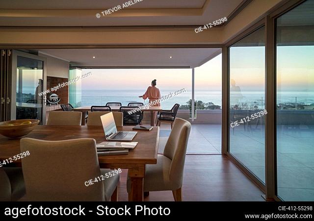 Woman relaxing on luxury balcony with sunset ocean view