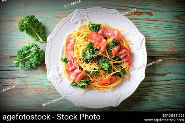 Delicious spicy linguine pasta with fried cabbage kale, bacon, garlic and parmesan on a white plate