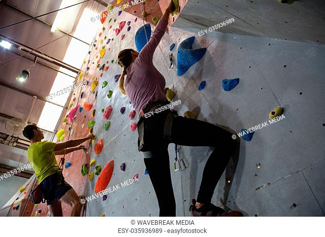 Low angle view of athletes rock climbing in fitness club