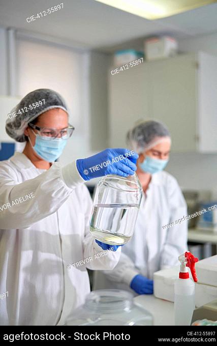 Scientists in protective workwear examining liquid in laboratory