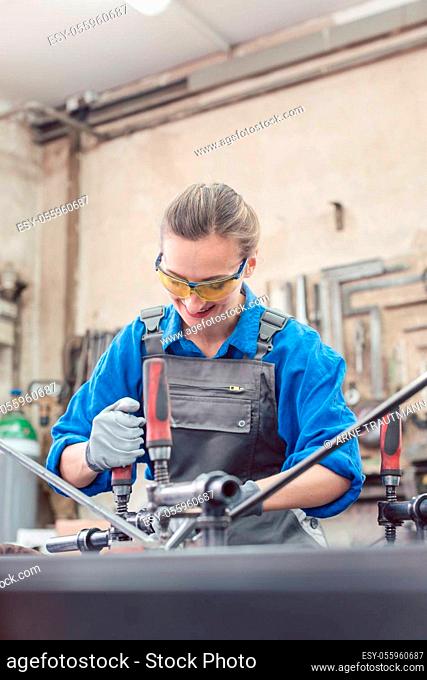 woman in Metal workshop with tools and workpiece working hard