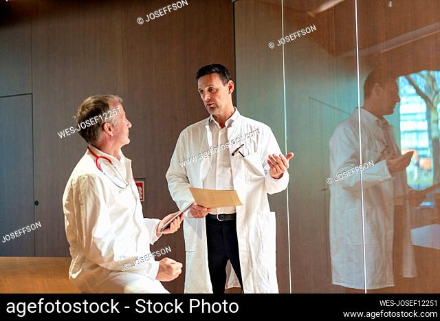 Healthcare workers wearing lab coat discussing with each other in hospital
