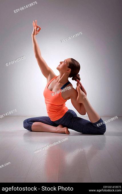 Beautiful sporty fit yogini woman practices yoga asana Eka pada rajakapotasana - one-legged pigeon pose in studio