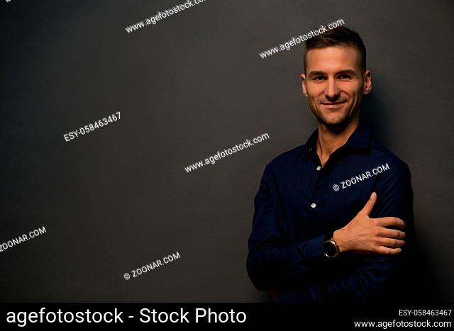 Picture of happy man posing over black background and posing for photographer. Handsome man smiling for camera with his hands crossed, folded, etc