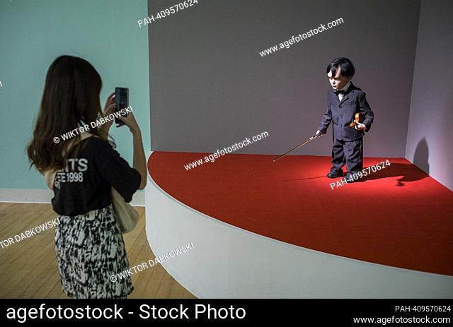 People look at sculpture of a dwarf violinist during the SUPERNATURAL: Sculptural Visions of the Body exhibition in Taipei
