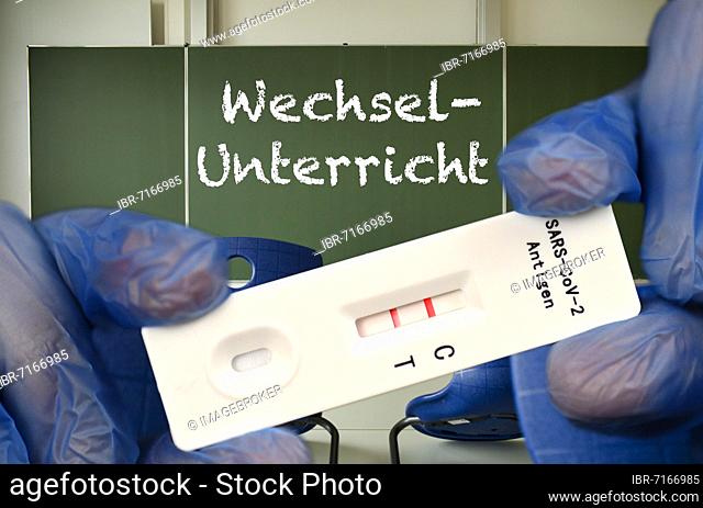 PHOTOMONTAGE, positive antigen rapid test, blackboard with inscription WECHSELUNTERRICHT, classroom, Corona crisis, Germany, Europe