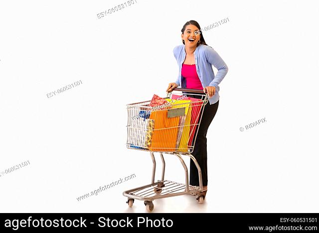 Indian girl posing in front of camera while moving with trolley after shopping