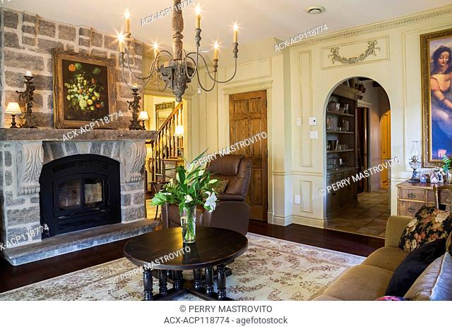 Grey natural stone fireplace and wooden round coffee table in the living room inside a 2006 reproduction of a 16th century Renaissance castle style residential...