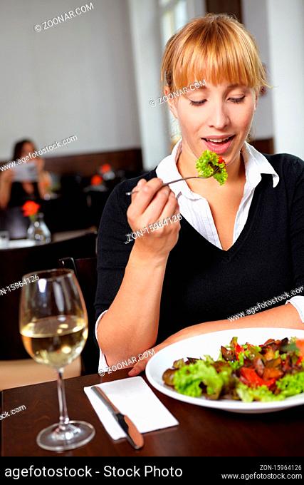 Frau isst einen grünen Salat im Restaurant