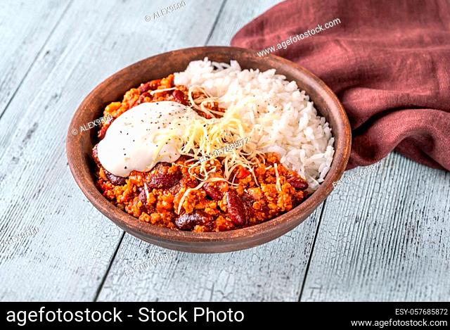 Chili con carne served with rice, grated cheese and tortilla chips