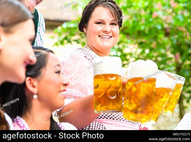 Waitress in beer garden serving drinks to three women and man
