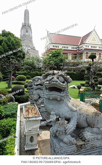 27 February 2018, Thailand, Bangkok: Chinese stone lion statue in front of the central prang (temple tower) in Wat Arun (Temple of Dawn)
