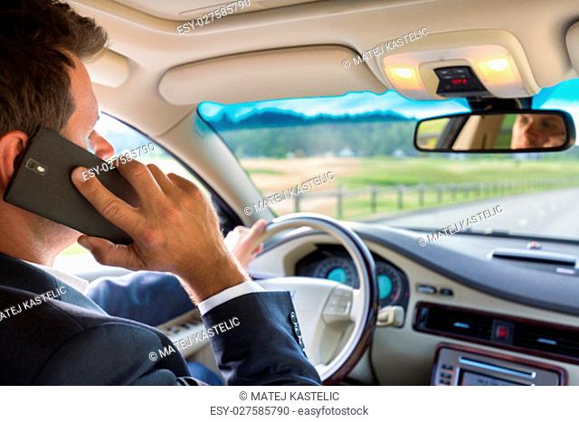Businessman talking on cell phone while driving and overtaking, not paying attention to the road and traffic