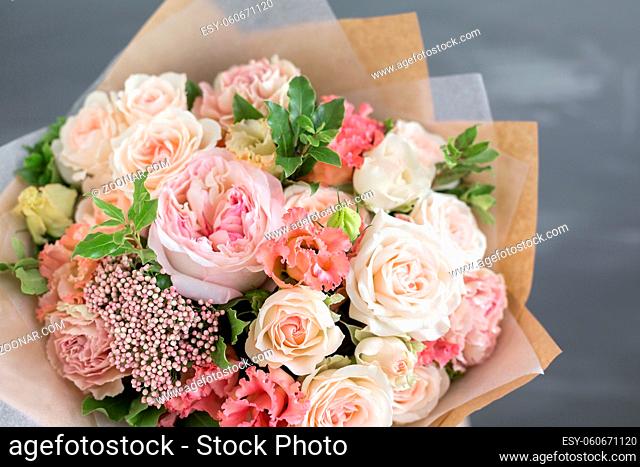 Bouquet in kraft paper. A simple bouquet of flowers and greens. on a gray background
