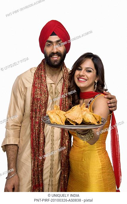 Sikh couple holding a plate of samosa the traditional Indian snack