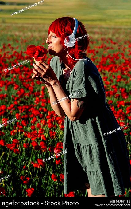 Woman with eyes closed smelling flowers on filed