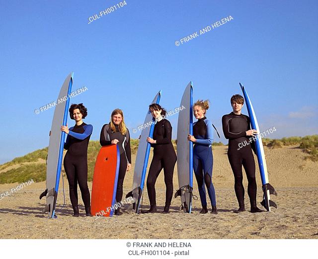 Five teenage surfers on a beach